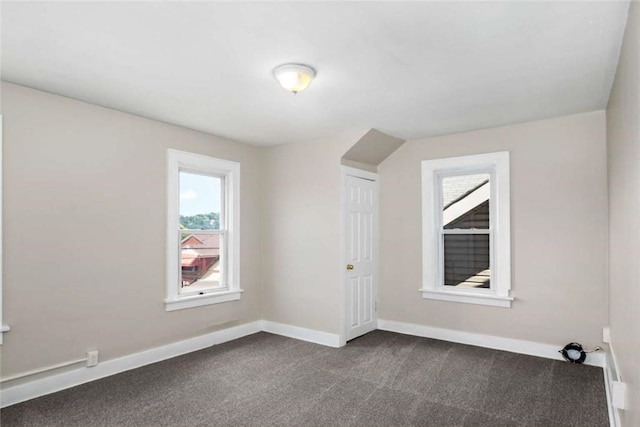 unfurnished room featuring dark carpet and baseboards