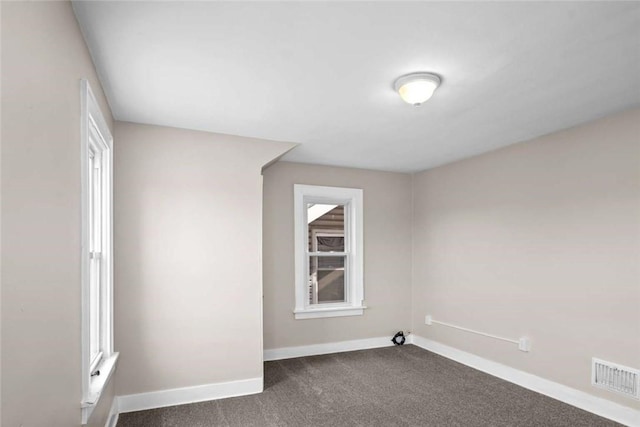 unfurnished room featuring baseboards, visible vents, and dark carpet