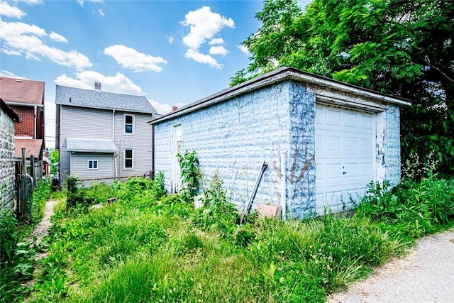 view of side of property featuring a garage, an outbuilding, and fence