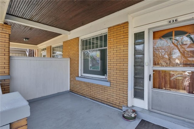 doorway to property with brick siding and a porch