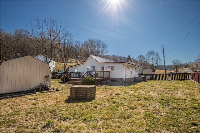 back of house with a fenced backyard, a yard, a storage shed, an outdoor structure, and a wooden deck