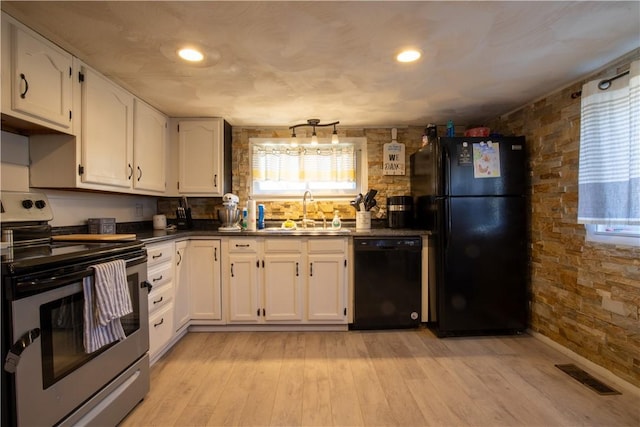 kitchen with dark countertops, visible vents, white cabinets, black appliances, and a sink