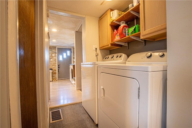 laundry room featuring light carpet, visible vents, cabinet space, and separate washer and dryer