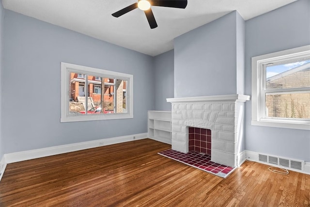 unfurnished living room featuring a fireplace, wood finished floors, visible vents, and baseboards