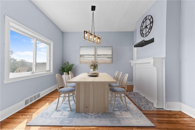 dining room with a notable chandelier, wood finished floors, visible vents, and baseboards