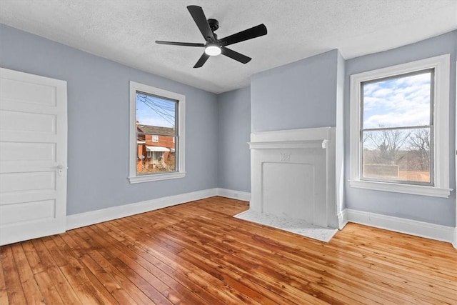 unfurnished living room with hardwood / wood-style floors, baseboards, and a wealth of natural light