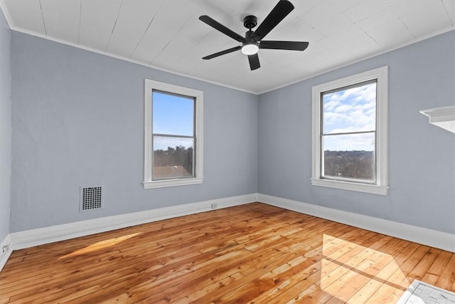 spare room with wood-type flooring, baseboards, visible vents, and a wealth of natural light