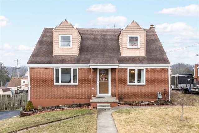 cape cod home featuring brick siding, a chimney, a front lawn, and fence