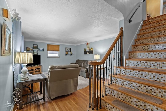 living area featuring stairway, a textured ceiling, and light wood finished floors