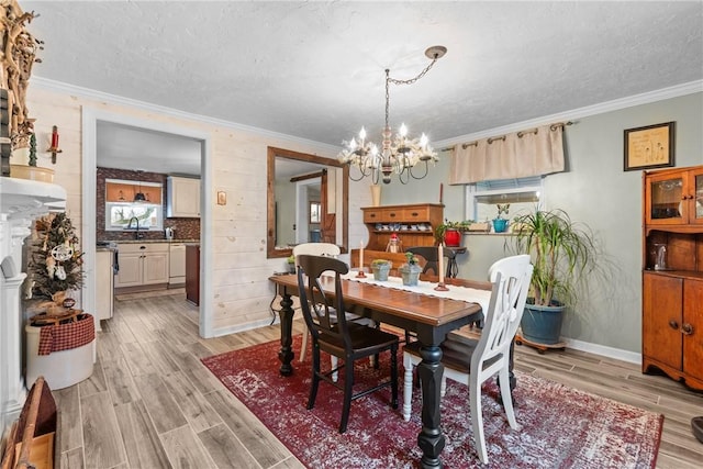 dining area featuring a notable chandelier, light wood-style flooring, a textured ceiling, and ornamental molding