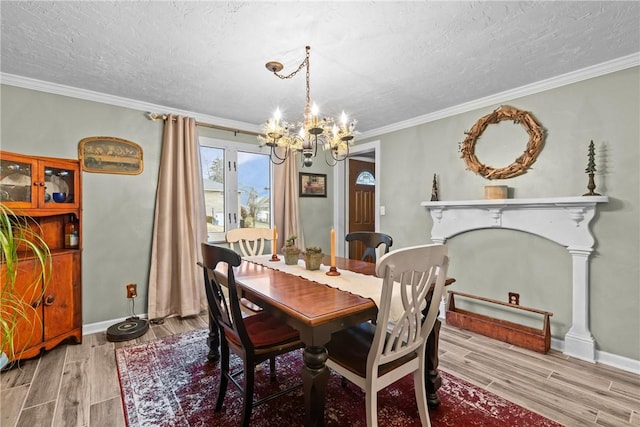 dining area featuring wood finish floors, a notable chandelier, a textured ceiling, crown molding, and baseboards