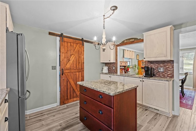 kitchen featuring a barn door, tasteful backsplash, wood tiled floor, and freestanding refrigerator