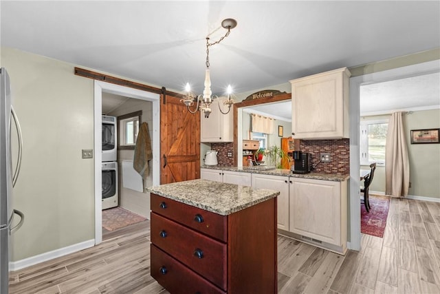 kitchen with a barn door, washer / dryer, decorative backsplash, and light wood finished floors