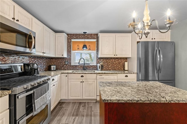 kitchen with backsplash, light wood-type flooring, light stone counters, appliances with stainless steel finishes, and a sink