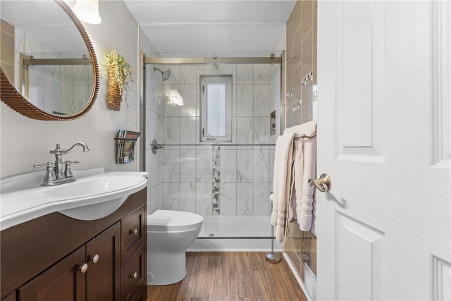 full bathroom featuring vanity, a shower stall, toilet, and wood finished floors