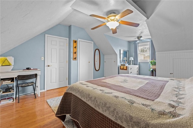 bedroom with lofted ceiling, a textured ceiling, wood finished floors, and a ceiling fan