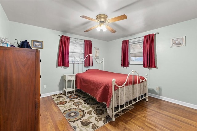 bedroom featuring a ceiling fan, baseboards, and wood finished floors