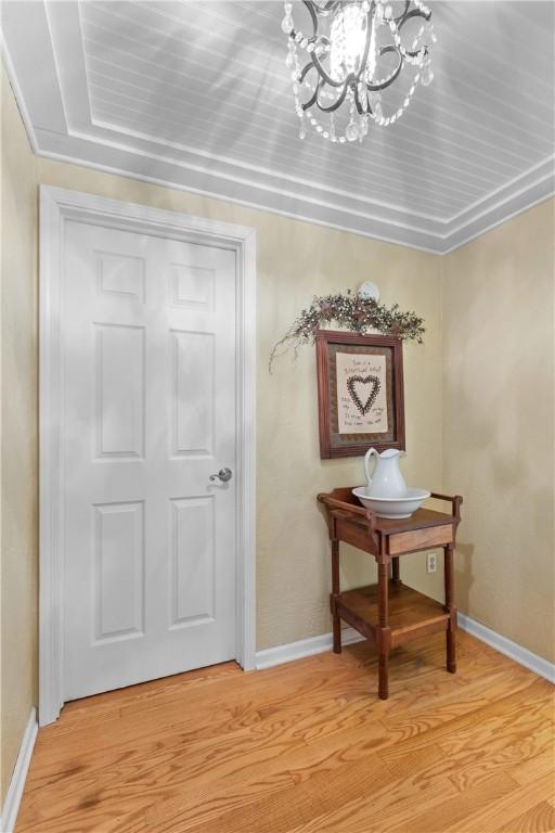 corridor featuring a notable chandelier, baseboards, and light wood-style floors