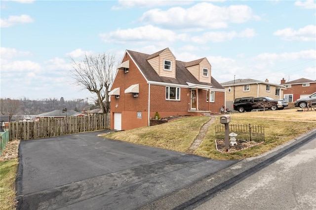 cape cod house featuring a front yard, fence, a garage, aphalt driveway, and brick siding