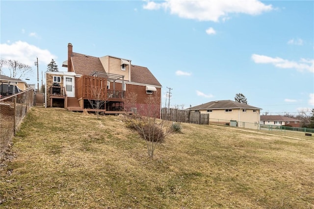 back of house featuring a yard, a wooden deck, a fenced backyard, and a chimney