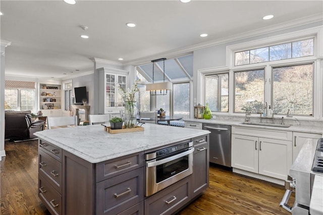 kitchen featuring ornamental molding, a sink, dark wood-style floors, white cabinetry, and stainless steel appliances