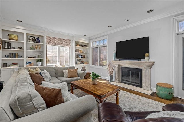 living room featuring wood finished floors, baseboards, a fireplace, recessed lighting, and crown molding