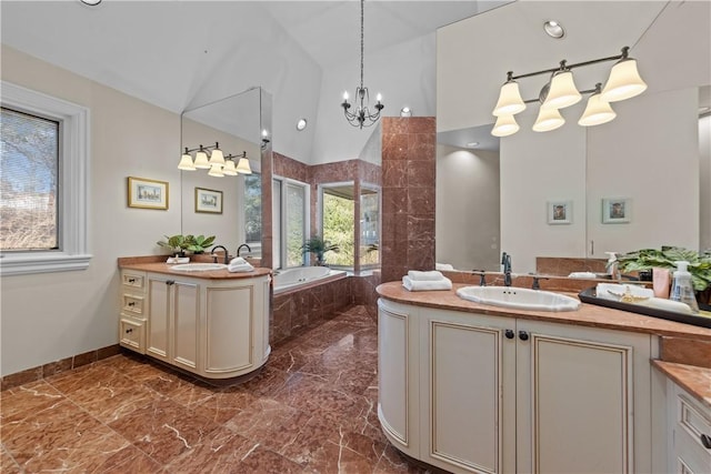 bathroom featuring marble finish floor, two vanities, lofted ceiling, and a sink