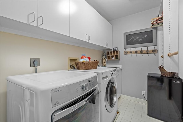 washroom featuring light tile patterned floors, baseboards, washing machine and clothes dryer, cabinet space, and a sink