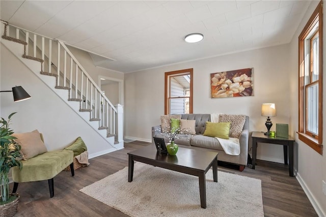 living area featuring plenty of natural light, stairs, baseboards, and dark wood-style flooring