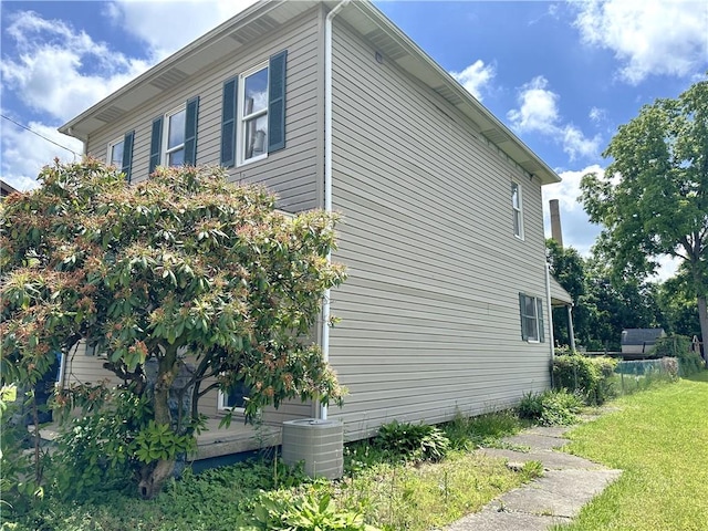 view of property exterior featuring a lawn and central AC