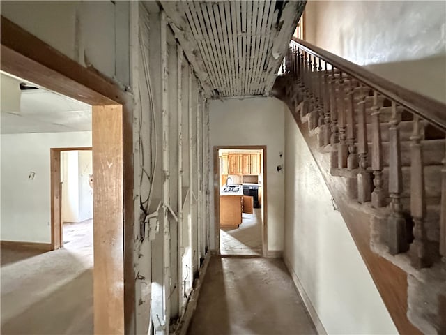 hall with baseboards and unfinished concrete floors