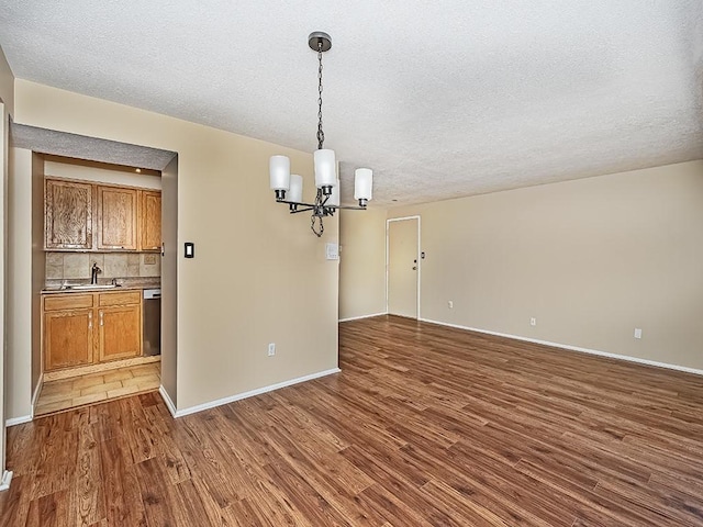 unfurnished dining area featuring baseboards, a textured ceiling, an inviting chandelier, and dark wood-style floors