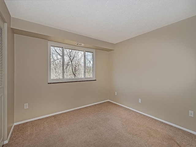 empty room with visible vents, baseboards, and carpet flooring