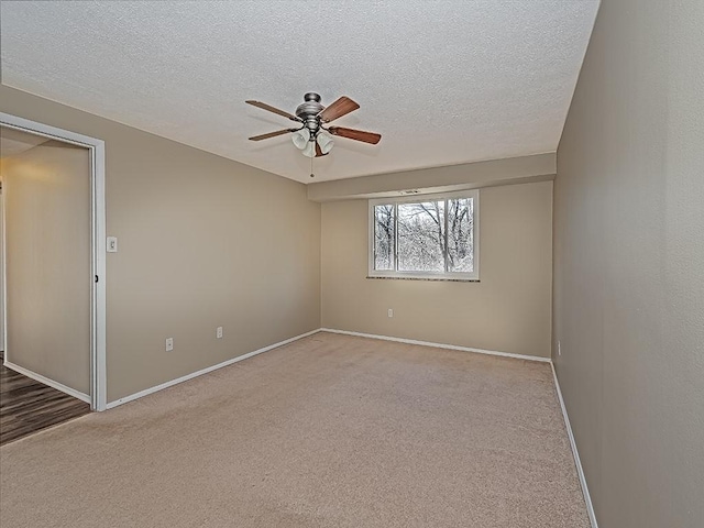 spare room with a ceiling fan, baseboards, carpet floors, and a textured ceiling