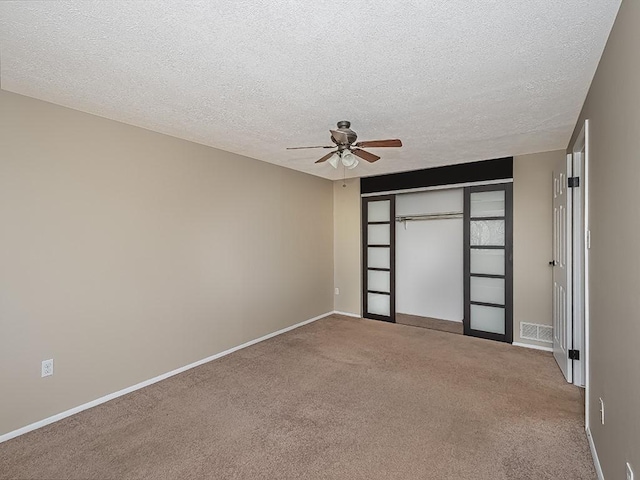 carpeted spare room with visible vents, baseboards, and a textured ceiling