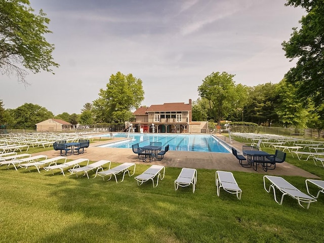 pool with a patio area, a lawn, and fence