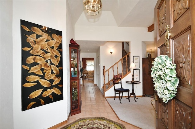 foyer featuring light tile patterned floors, baseboards, and stairs