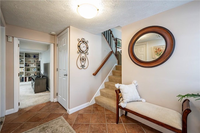 stairs with baseboards, a textured ceiling, and tile patterned flooring