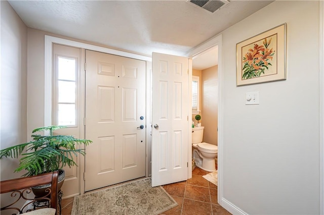 foyer entrance featuring dark tile patterned floors, visible vents, and baseboards