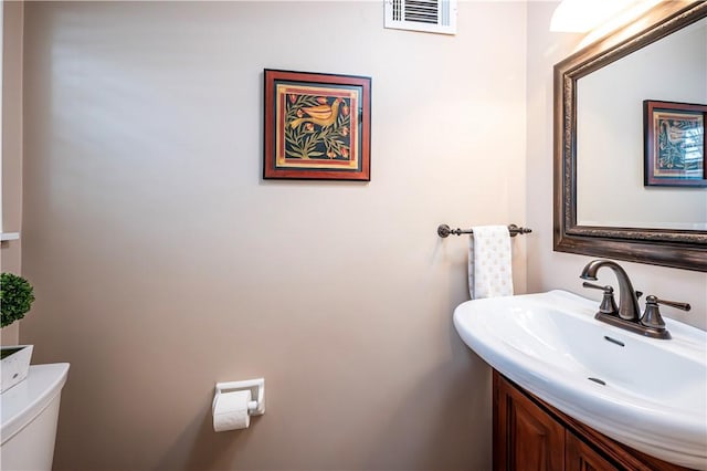 half bathroom featuring a sink, visible vents, and toilet