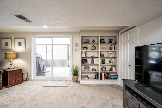 living area featuring visible vents, carpet, and a textured ceiling