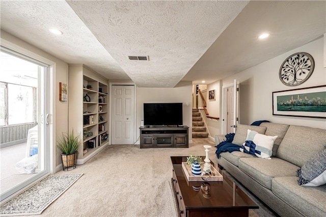 living area featuring stairs, light colored carpet, visible vents, and a textured ceiling