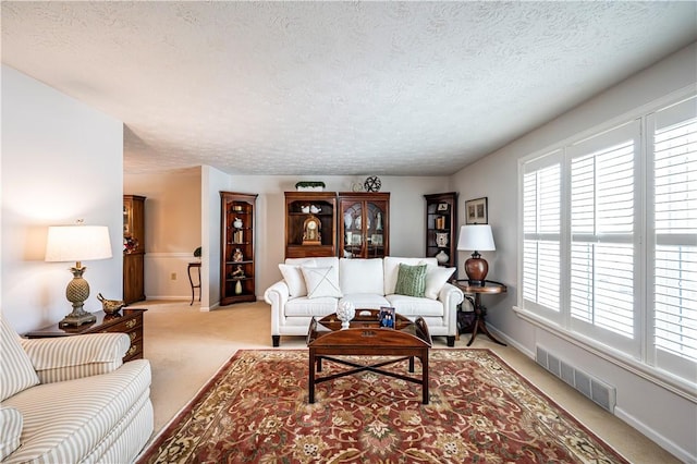 living room featuring a textured ceiling, baseboards, visible vents, and light carpet