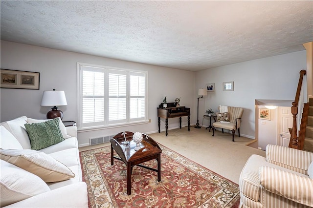 carpeted living area with visible vents, baseboards, and a textured ceiling