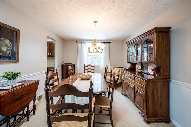 dining room with a chandelier, a textured ceiling, and light carpet