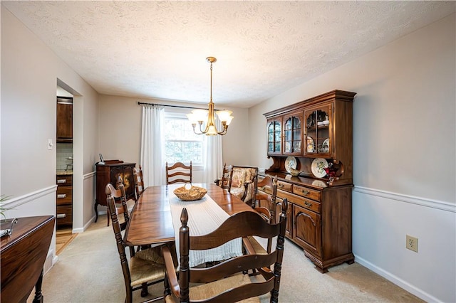 dining space featuring a notable chandelier, baseboards, light colored carpet, and a textured ceiling