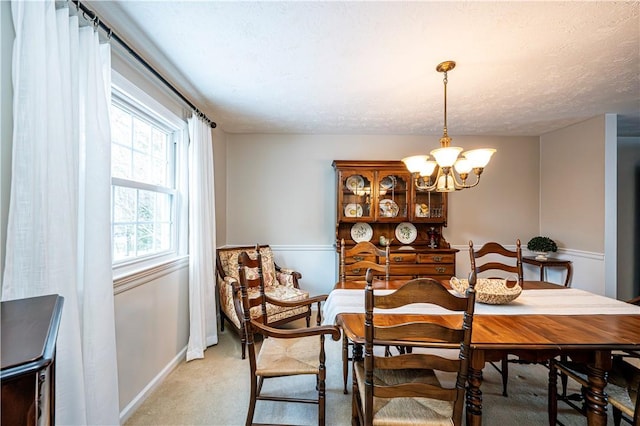 dining room featuring a chandelier, a textured ceiling, and light carpet