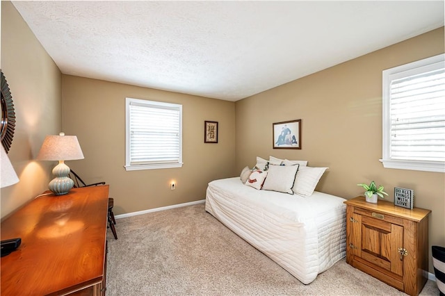 carpeted bedroom with multiple windows, baseboards, and a textured ceiling