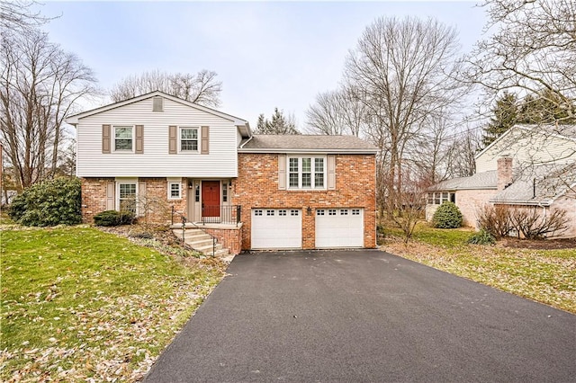 tri-level home featuring brick siding, driveway, a front yard, and a garage