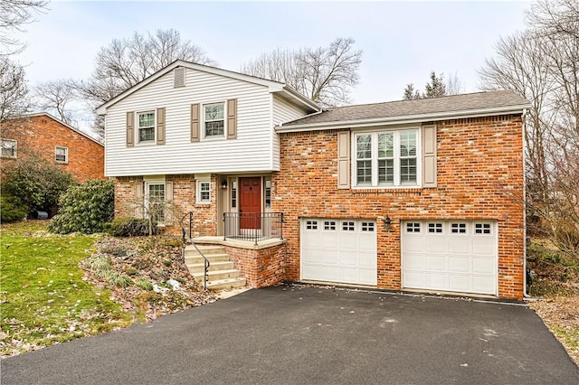 split level home featuring aphalt driveway, an attached garage, and brick siding